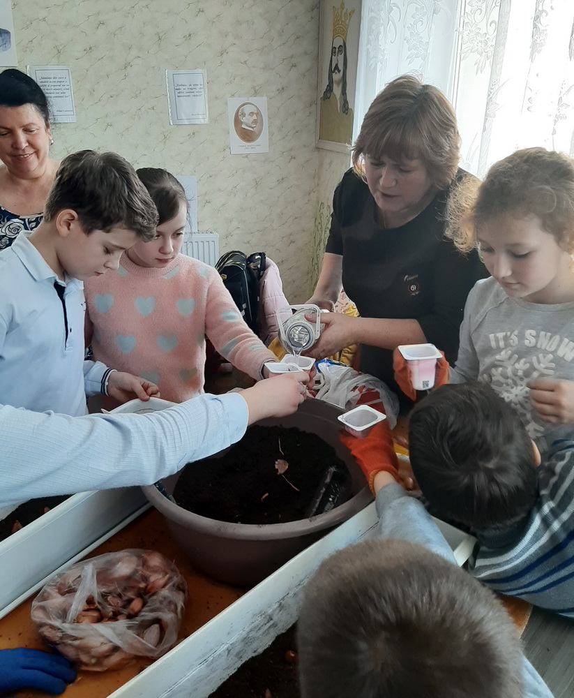 Учитель Галина Йурас объясняет и помогает ребятам сажать цветы